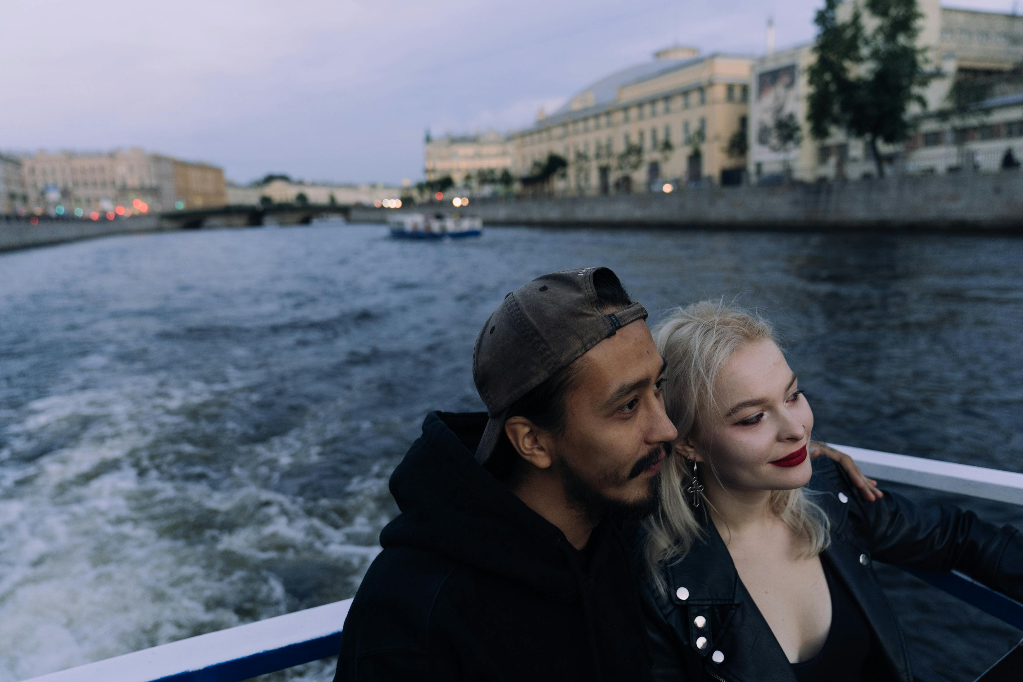 一对浪漫的夫妇在黄昏时分，乘船游览于宁静的河上，四周环绕着城市景观