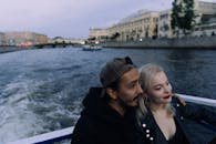 一对浪漫的夫妇在黄昏时分，乘船游览于宁静的河上，四周环绕着城市景观