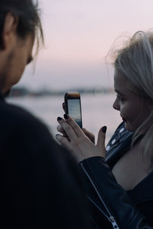 Young Woman Taking Pictures of the Sunset with a Smartphone 