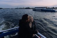 日落时分，一对夫妇在渡轮上俯瞰平静的海面，共享浪漫时光