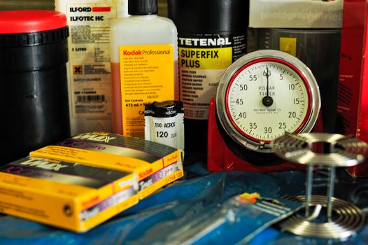 Collection of analog photography items including film rolls, developer liquids, and a Kodak timer for darkroom processing.