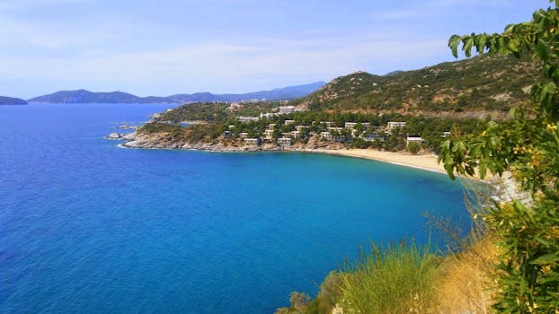 Breathtaking view of the vibrant Greek coast near a charming village, featuring clear blue waters and lush greenery.