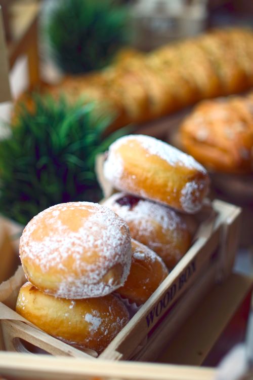 Free Close-up of freshly powdered doughnuts on a wooden tray with a vibrant background. Perfect for food photography. Stock Photo