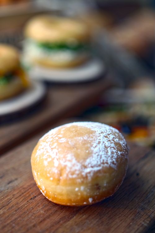 Free Close-up of a delicious glazed doughnut dusted with powdered sugar on a wooden board. Stock Photo