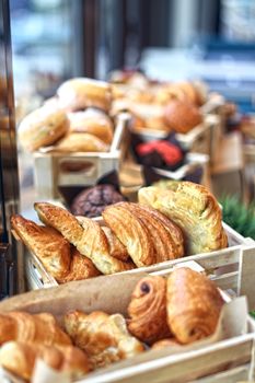 A close-up of fresh croissants and breads in a wooden display, perfect for food presentations.