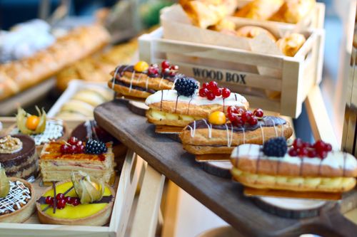 Free A colorful assortment of French pastries on wooden boards, perfect for a gourmet dessert table. Stock Photo