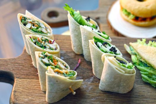 A close-up of homemade nutritious wraps with fresh ingredients on a wooden board.