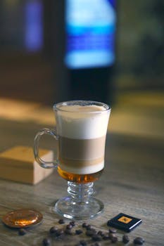 Upscale latte macchiato in a glass on a wooden table with coffee beans, creating a cozy and elegant ambiance.