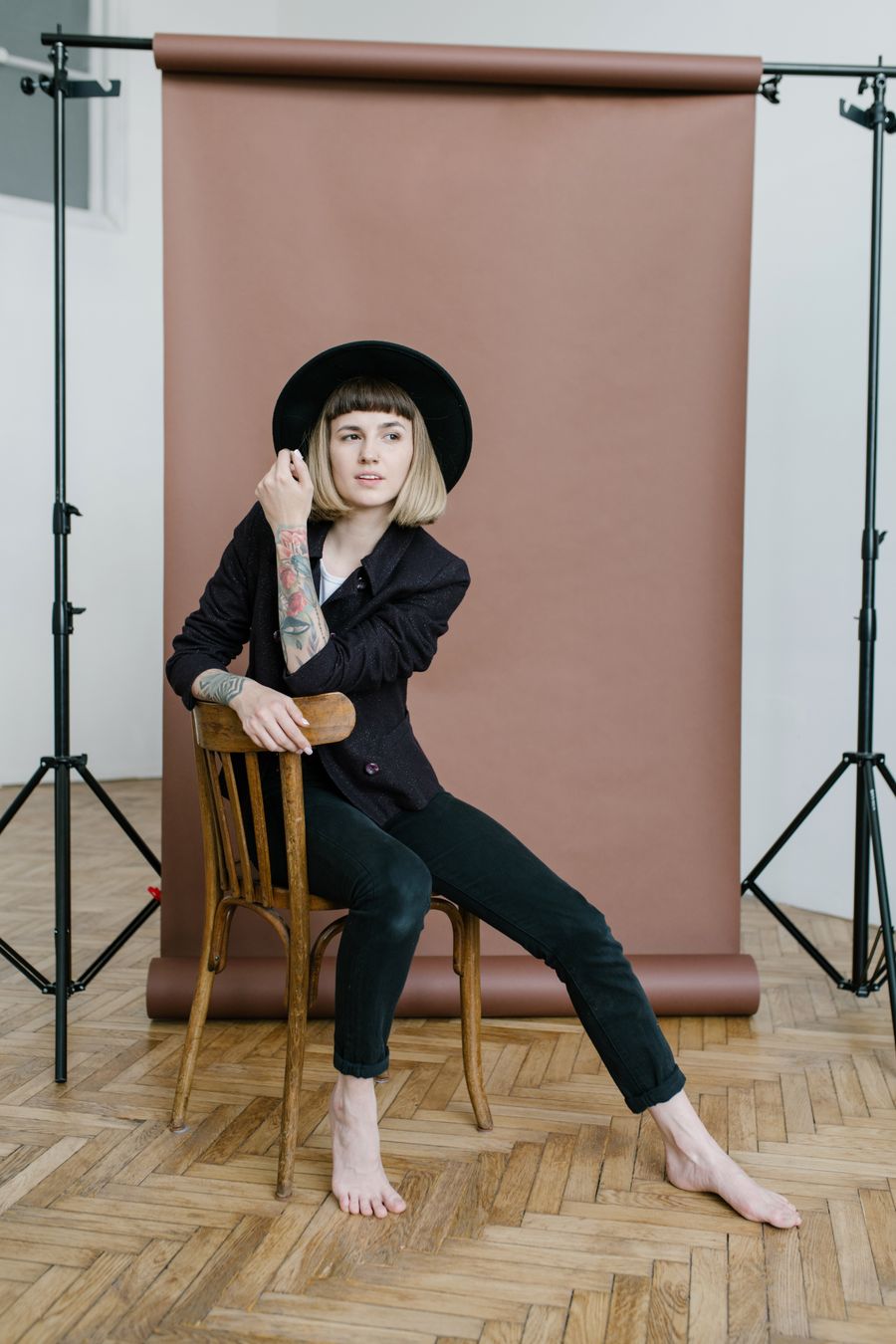 Woman seated on a wooden chair in front of a seamless studio backdrop — photo by Julia Volk on Pexels