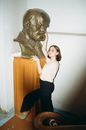 Woman in White Shirt and Black Pants Standing Beside Lion Statue