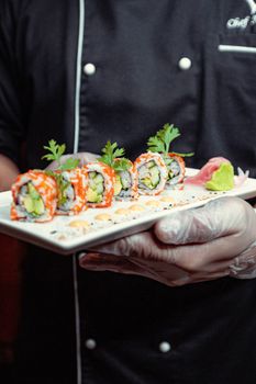 Close-up of vibrant sushi rolls served on a plate by a chef in Dubai.