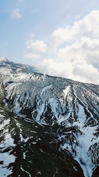 Breathtaking snowy mountain peaks under a clear blue sky in Aso City, Kumamoto, Japan.