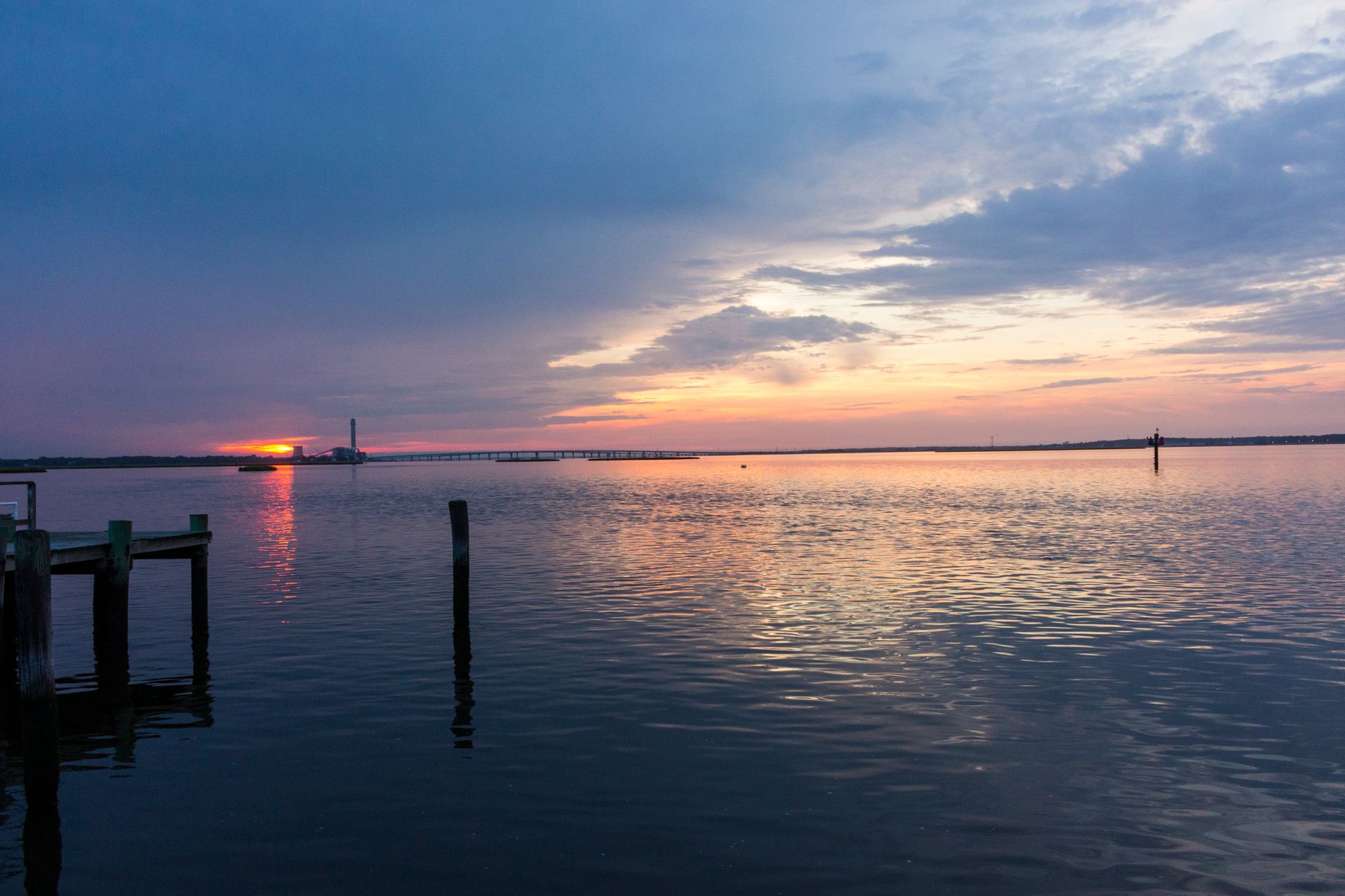 Beautiful sunset over calm waters and wooden dock in Ocean City, NJ, showcasing a serene seascape.