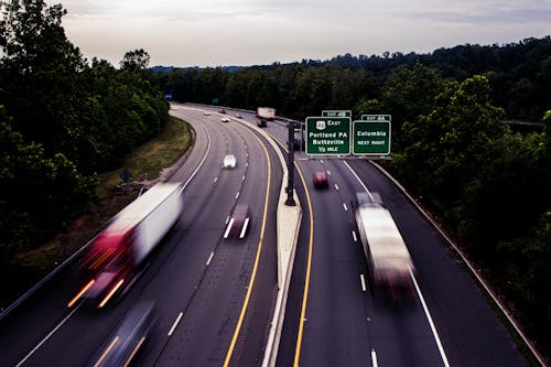 Free Fast Moving Cars on an Expressway Between Green Trees Stock Photo