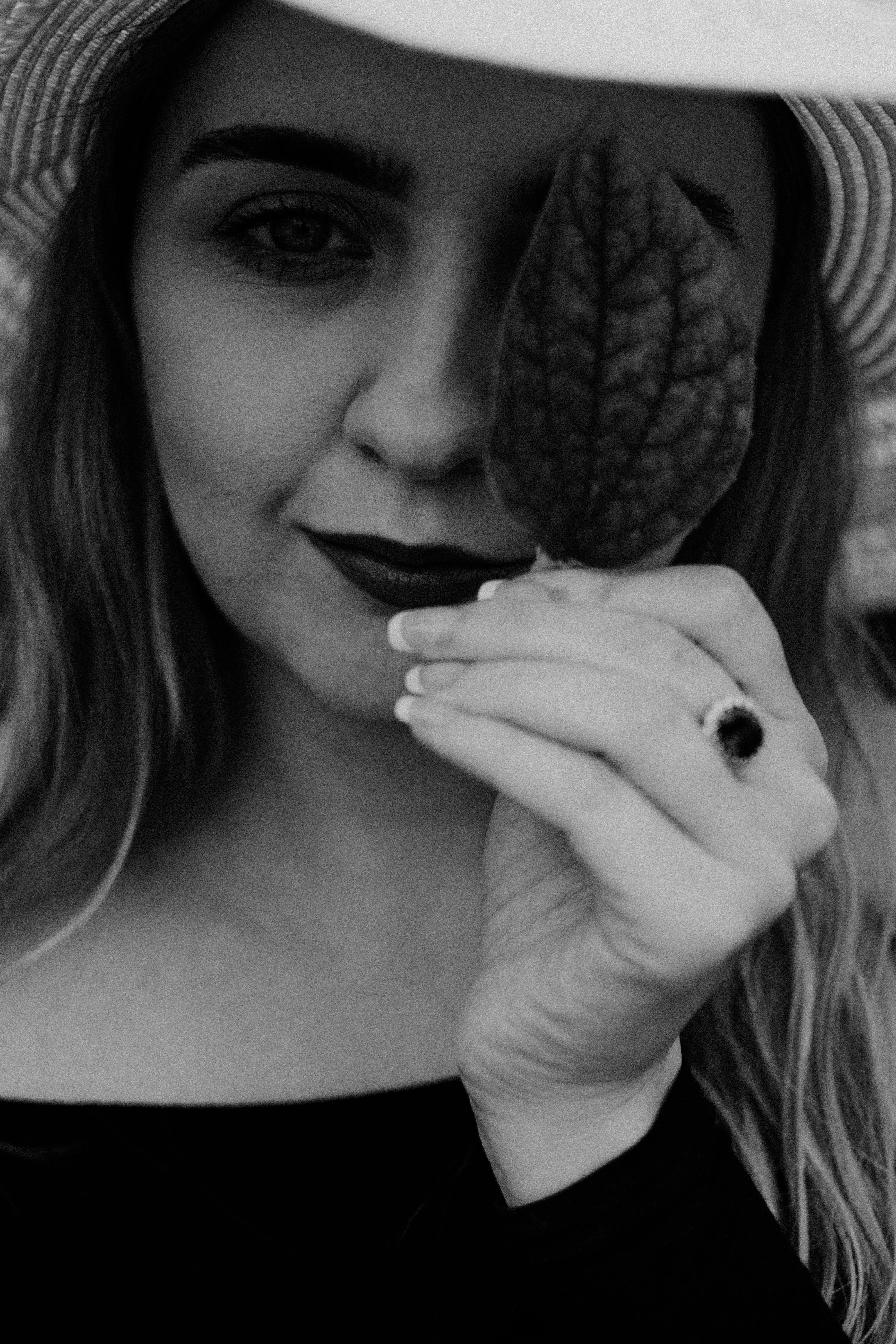 Artistic black and white portrait of a woman holding a leaf, showcasing elegance and nature.