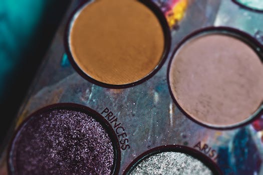 Vivid close-up of a multicolored eyeshadow palette with glitter and matte shades.