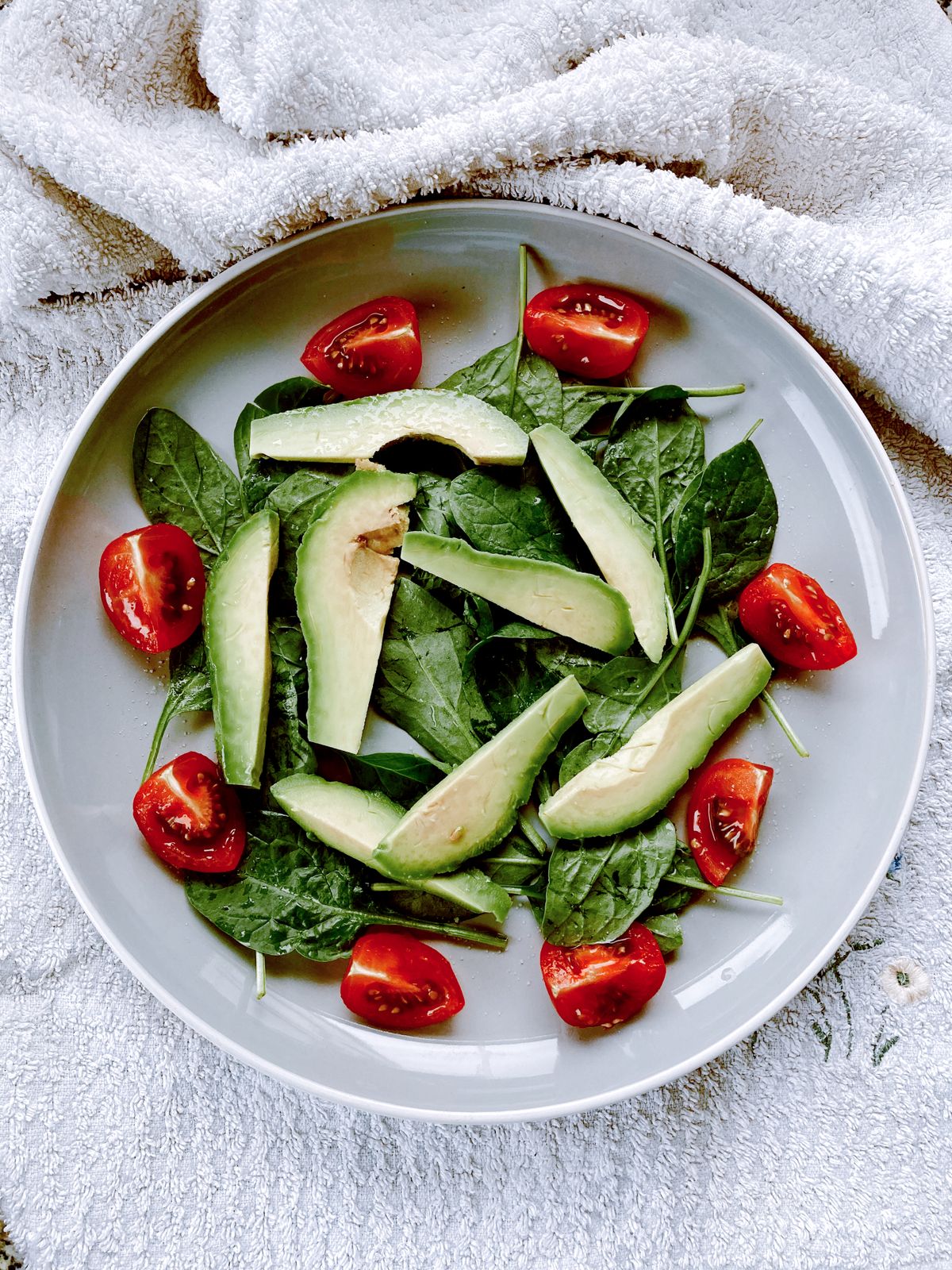 Salada com folhas, abacate e tomates cereja no prato, exemplo de refeição com vegetais e gordura boa