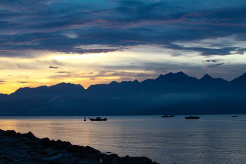 Free A serene silhouette of boats during dawn with mountains in the backdrop in Đà Nẵng, Vietnam. Stock Photo
