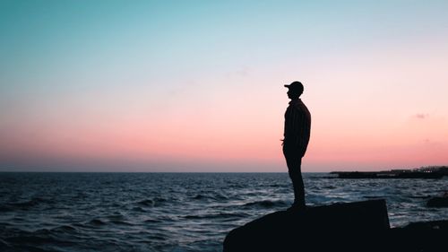 Free A man stands silhouetted against a colorful sunset sky on the coast of Alexandria, Egypt. Stock Photo