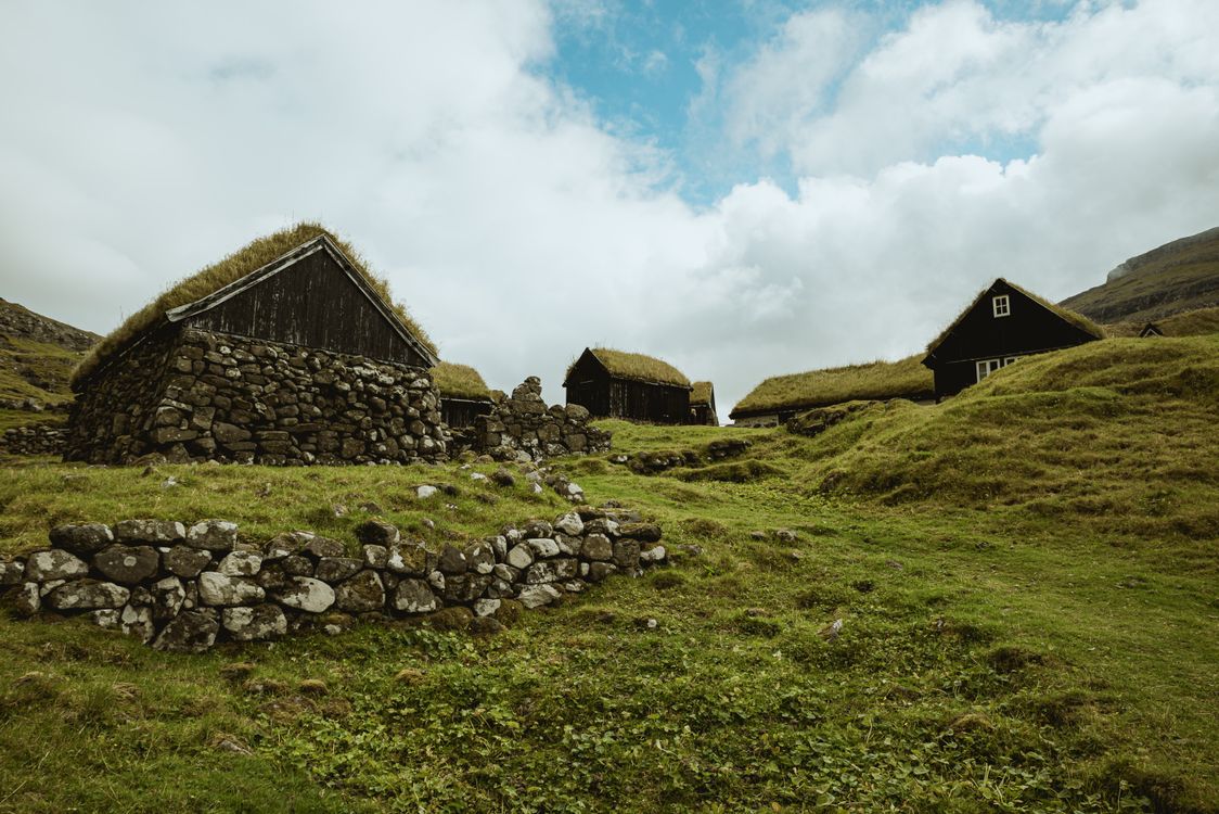 Wooden Houses on Green Grass Field Under Cloudy Sky · Free Stock Photo