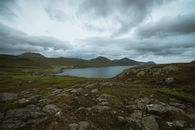 Gray Rocky Shore Near Body of Water Under Cloudy Sky