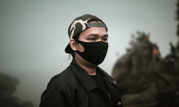 Man In A Face Mask Wearing A Baseball Cap Backwards 