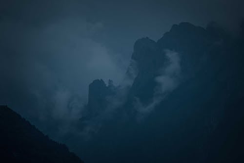 Dark rough hill peak under gloomy cloudy sky in countryside at mysterious night