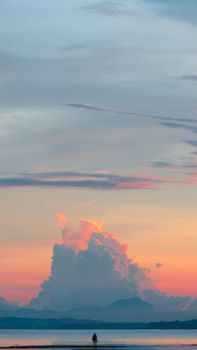 Silhouette against a dramatic sunset sky on a serene beach, perfect for relaxation themes.