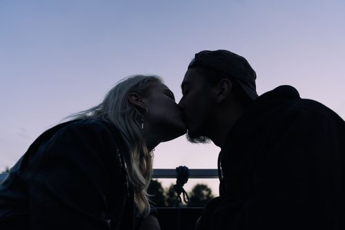 Free Silhouette of a couple kissing at twilight, creating a romantic and intimate mood. Stock Photo