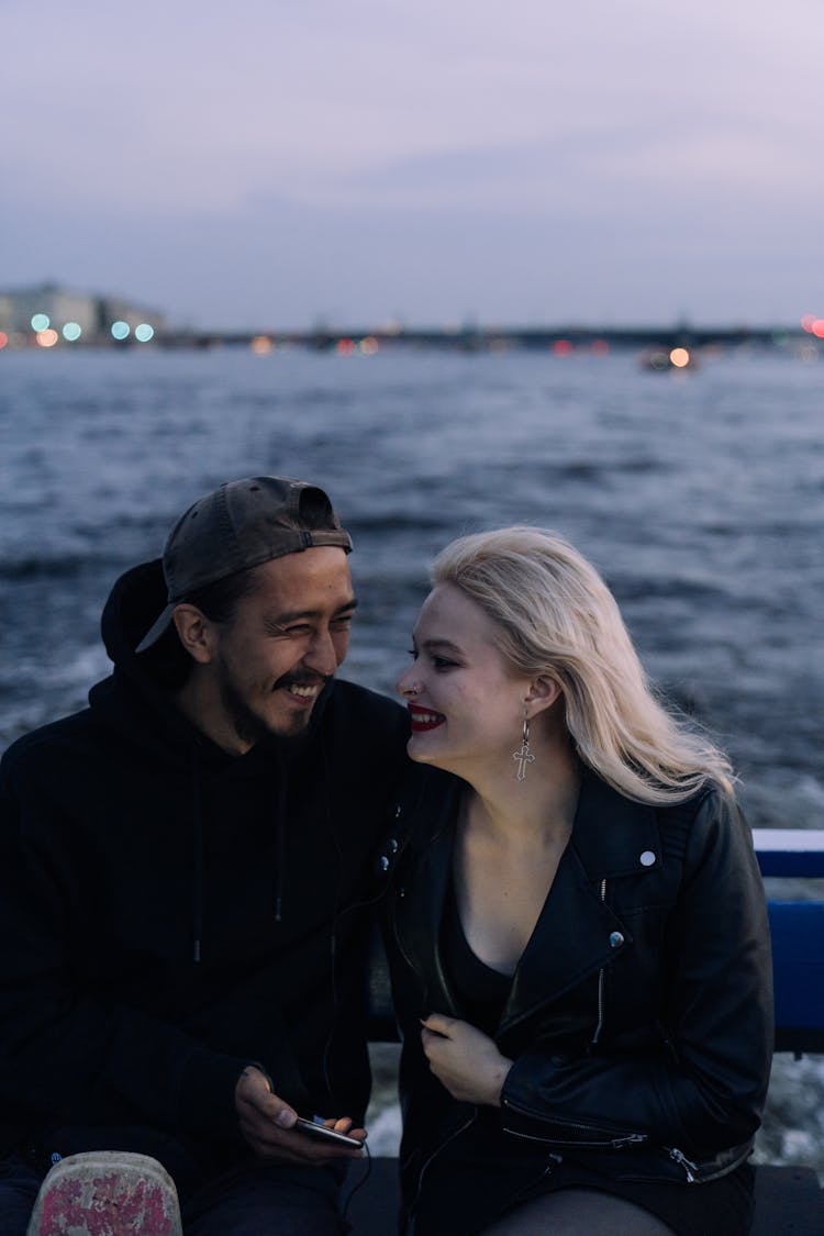 A Happy Couple Sitting On The Deck Of A Boat While Looking At Each Other