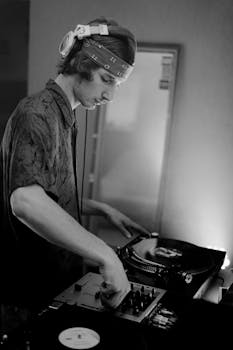 A young DJ with headphones mixes music using vinyl records indoors.