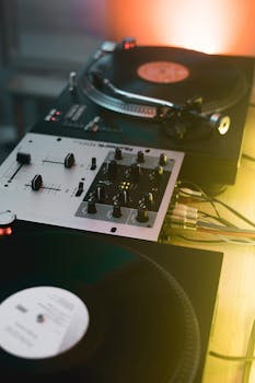 Close-up of a DJ setup with turntables and a mixer in a vibrant indoor setting.