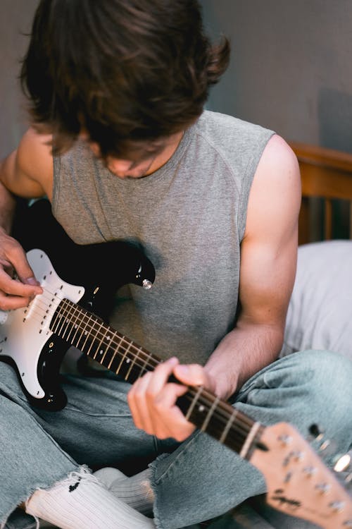 Man in Gray Tank Top Playing White Stratocaster Electric Guitar