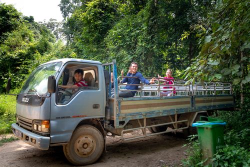 Free Cheerful travelers riding in truck with Asian driver during excursion in tropical green forest Stock Photo