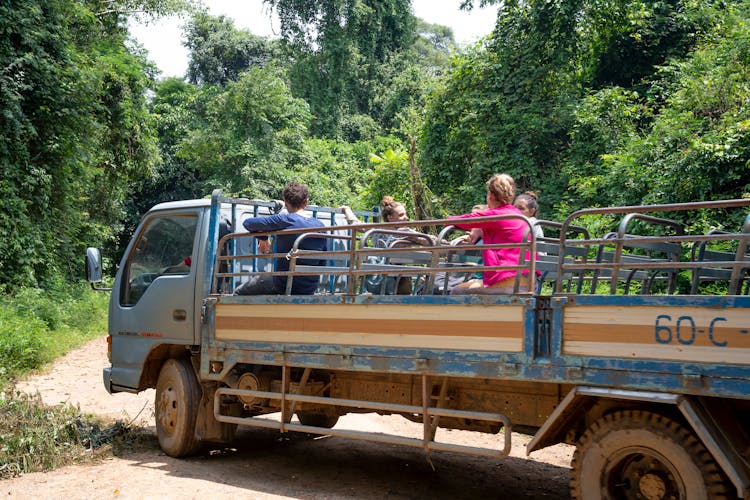 Group Of Tourists Having Excursion In Truck Driving Through Woods