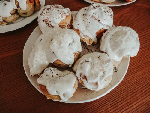 Free Close-up of freshly baked homemade cinnamon rolls covered with rich icing on a plate. Perfect for dessert lovers. Stock Photo