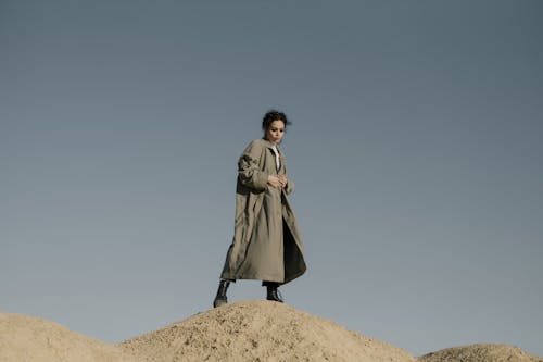 Woman in Gray Coat Standing on Brown Rock
