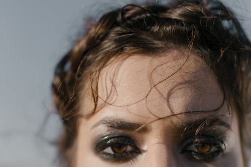 Free Close-up portrait showcasing bold eye makeup and expressive eyes outdoors. Stock Photo