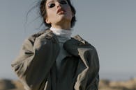 一位穿着风衣的时尚女性在阳光明媚的日子里在户外摆姿势