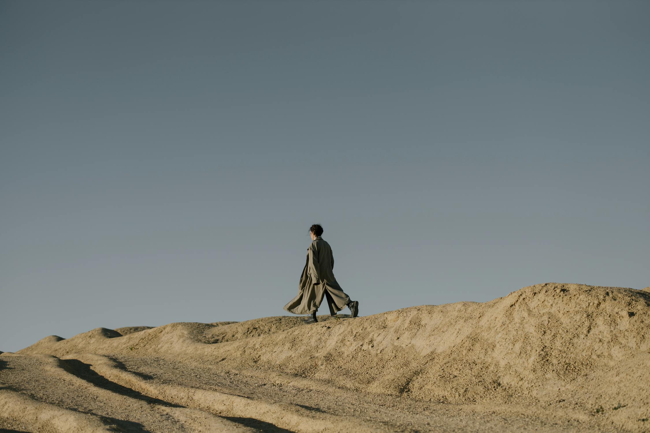 Man in Black Jacket Walking on Brown Sand · Free Stock Photo