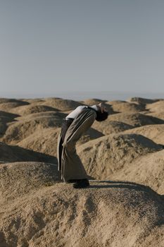 一位时尚女子穿着风衣，在广阔的沙漠中戏剧性地摆出姿势