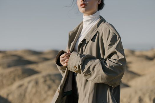 一位穿着风衣的时尚女士自信地站在广阔的沙漠中