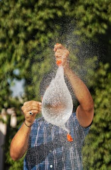 A vibrant image capturing the moment a water balloon bursts, with droplets frozen in mid-air.