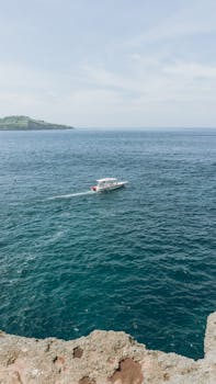 一艘孤船在晴朗的天空下，航行于广阔的海面，展现出宁静的旅行与探索
