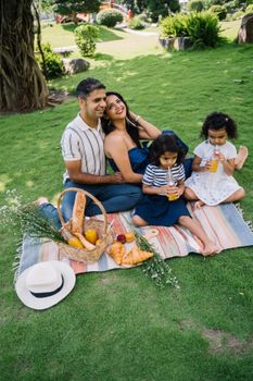 Man and Woman Sitting on Picnic Mat on Green Grass Field