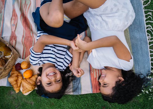 Free Girls Playing Lying Down on a Picnic Blanket Stock Photo