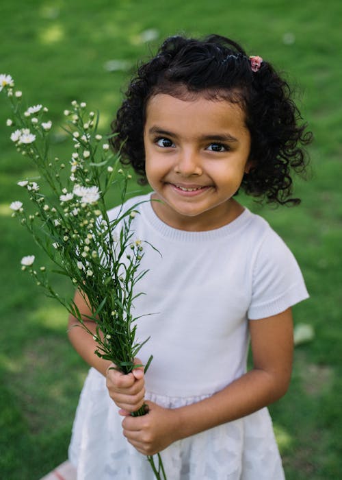 Free Girl in White Dress Holding a Bunch of Flowers Stock Photo