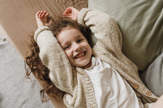 那个卷发的快乐孩子，舒适地躺在室内，微笑着拥抱温暖和幸福