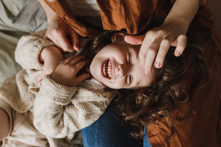 A Child In A Sweater Lying On A Person's Lap