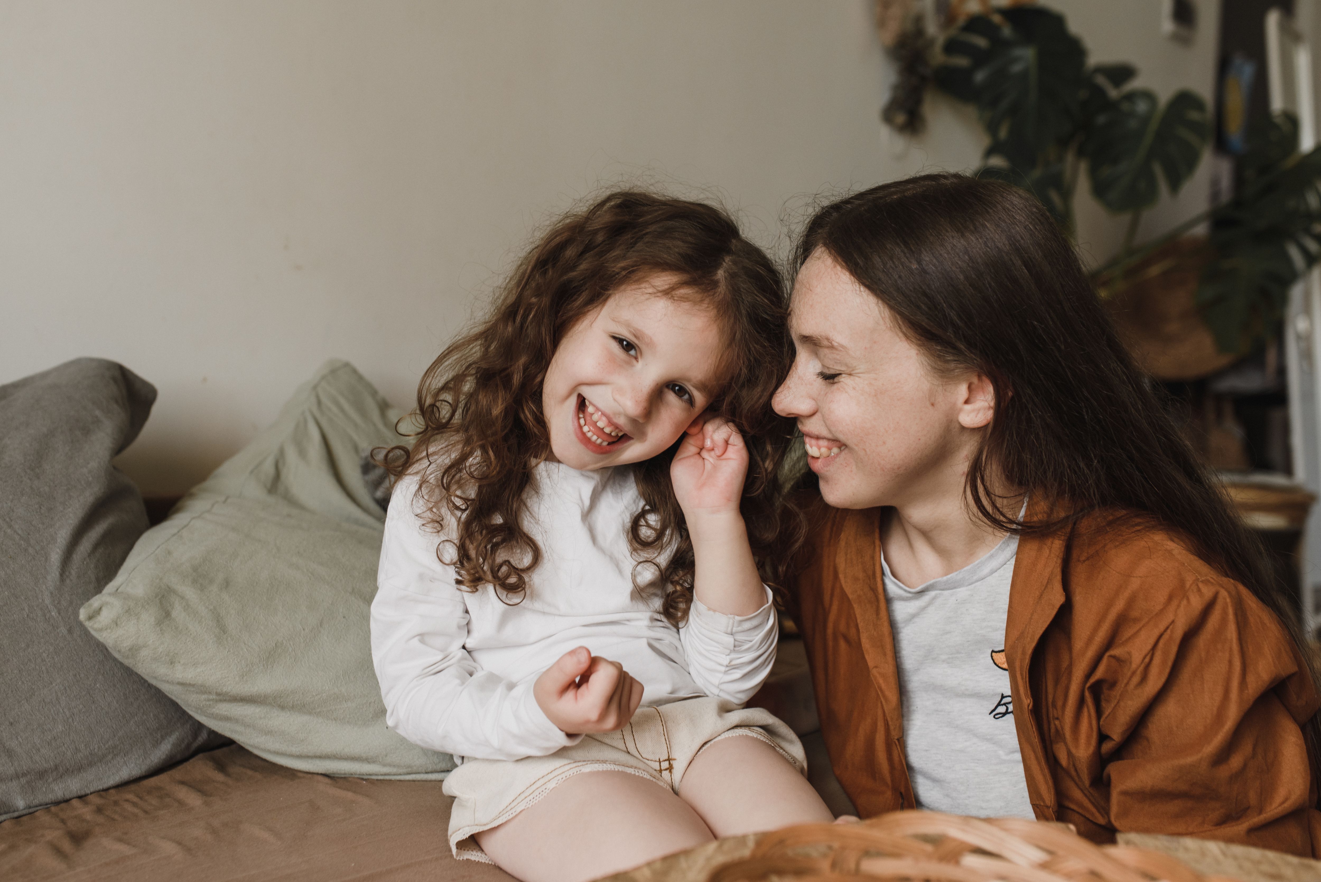 Une mère et sa fille heureuses profitant d'un moment tendre à l'intérieur, échangeant des sourires.